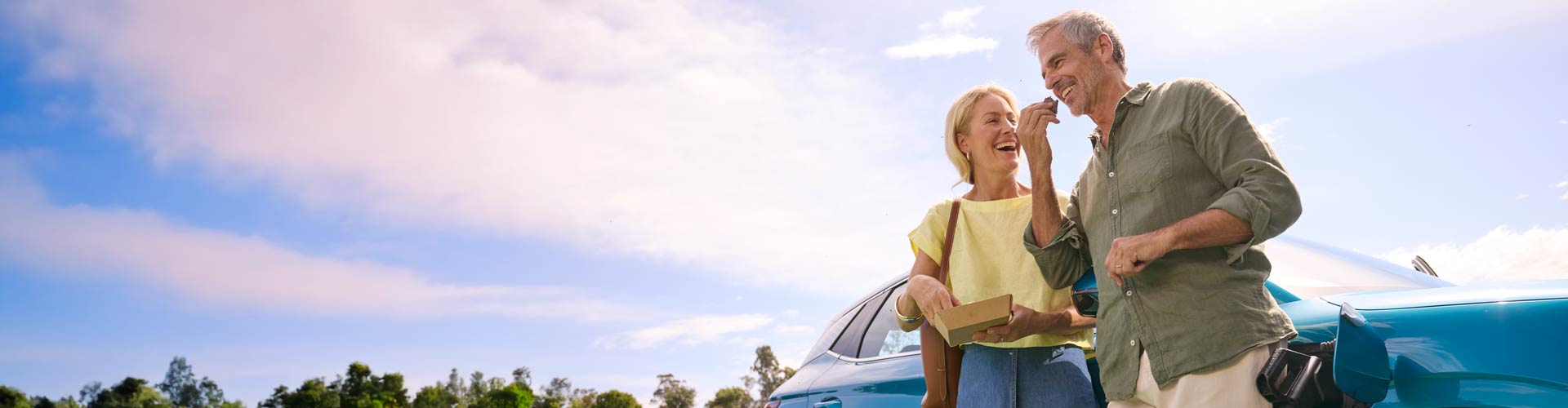 A couple eating food standing next to a charging EV