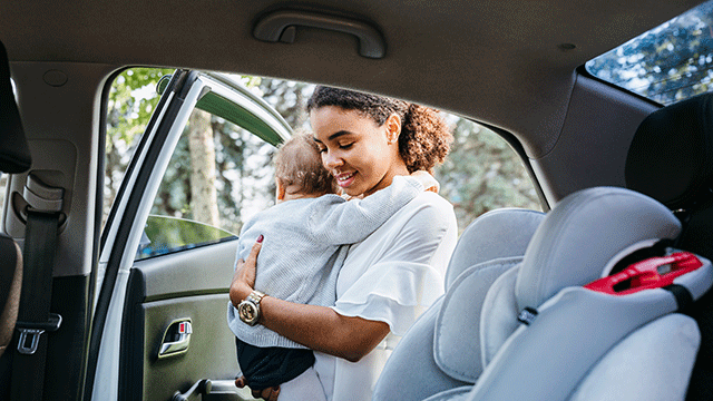 mother putting baby daughter in a car seat