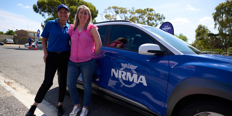 2 drivers smiling in front of blue nrma vehicle