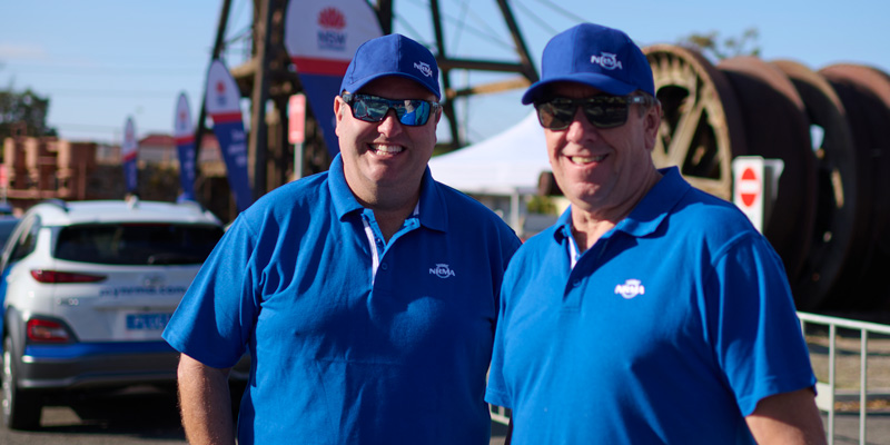 2 male nrma volunteers wearing a blue shirt and cap