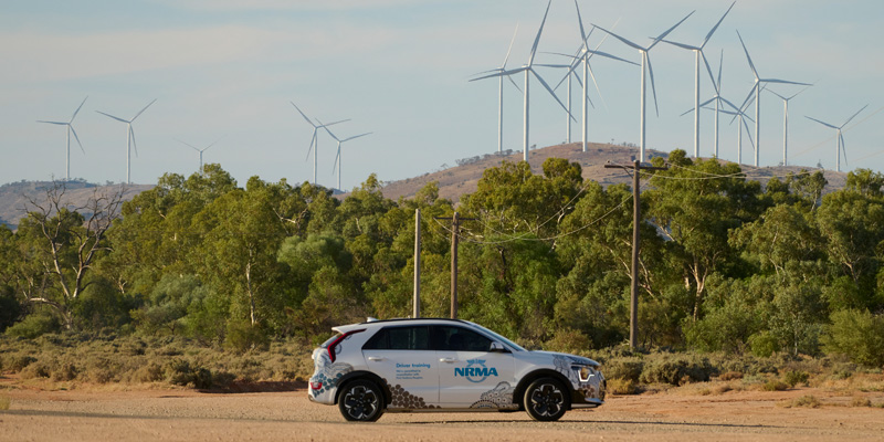 white nrma vehicle parked on the road with windmills in the background