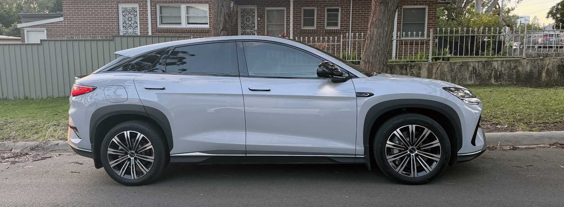 A light grey BYD Sealion 7 seen from the side on a street