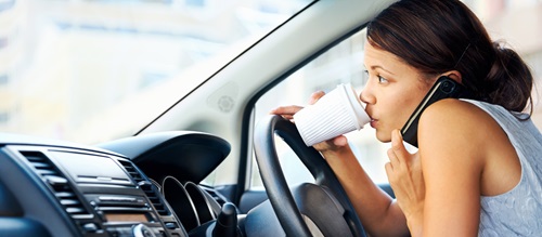 Woman talking on the phone and drinking coffee while driving car