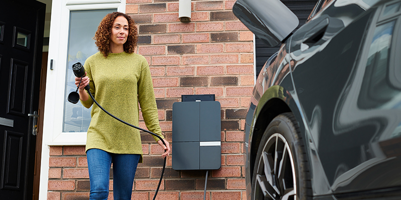 Woman charging electric vehicle at home