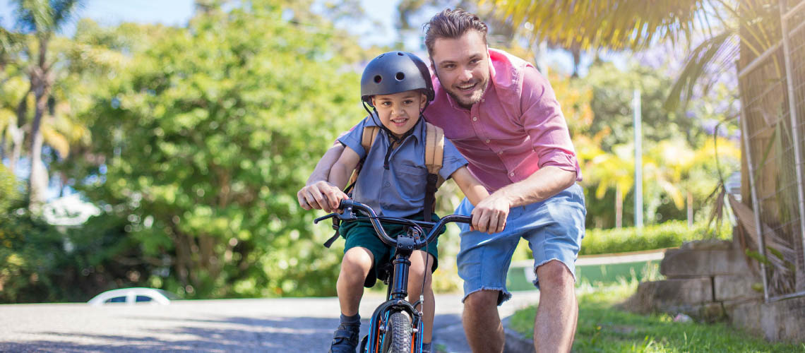 Father teaching son how to ride bicycle | Motoring education