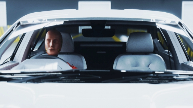 crash test dummy sitting in the drivers seat of a grey car