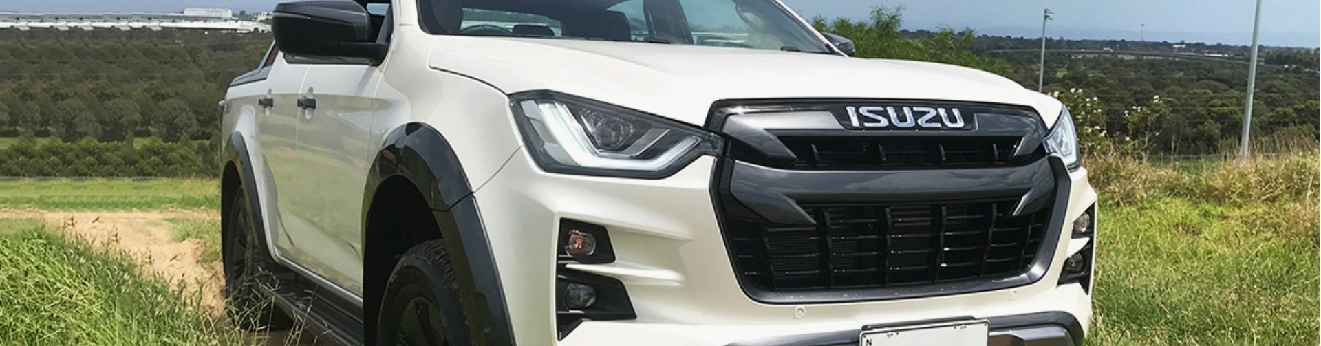 A white 2021 Isuzu D-Max driving along a dirt road.