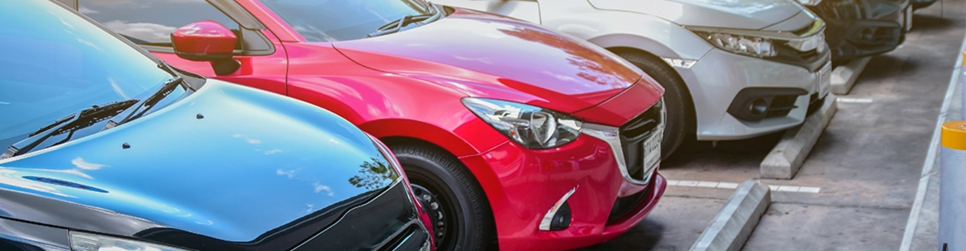 A row of cars parked side-by-side in a parking lot.