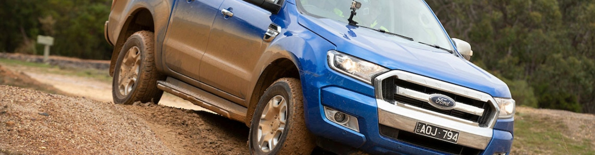 A blue Ford Ranger driving down a steep dirt patch.