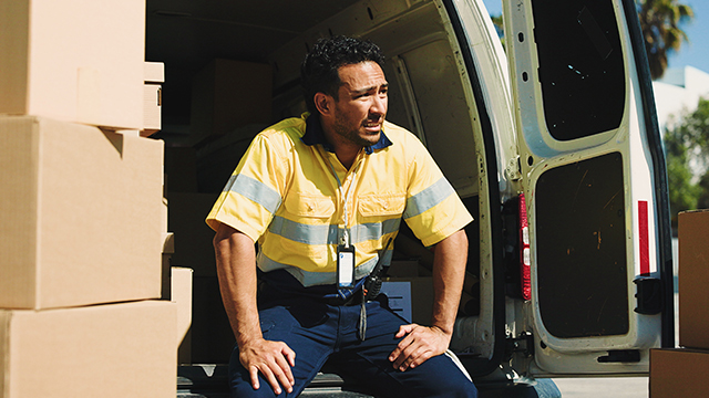 delivery man sitting down in white van looking fatigued
