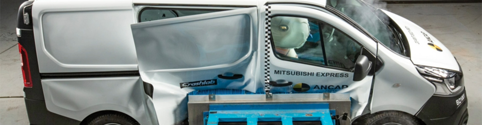 Side view of a white Mitsubishi Express during crash testing.