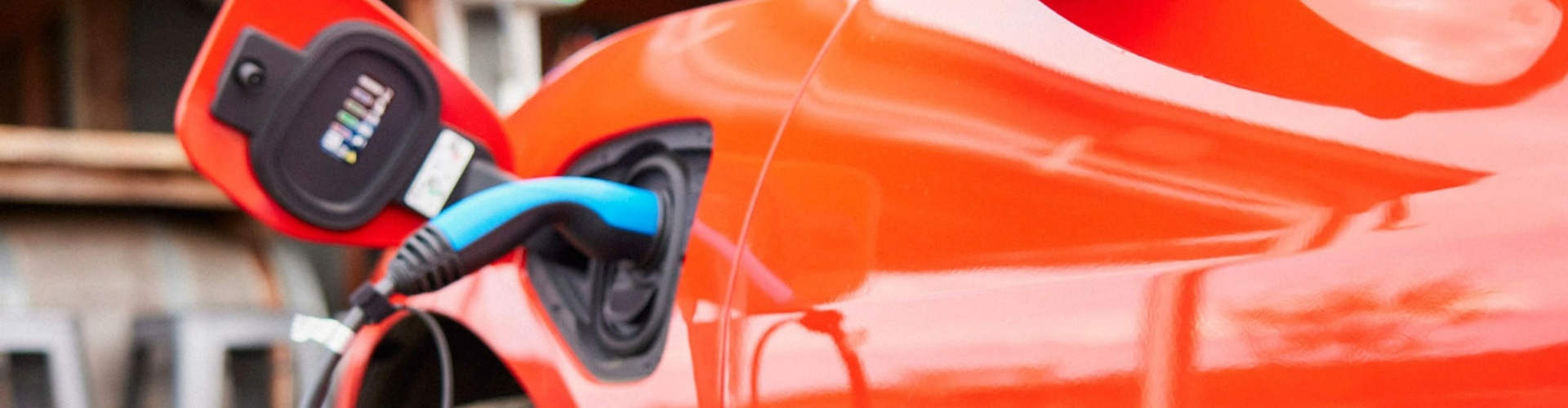 Side view of an orange electric vehicle charging.