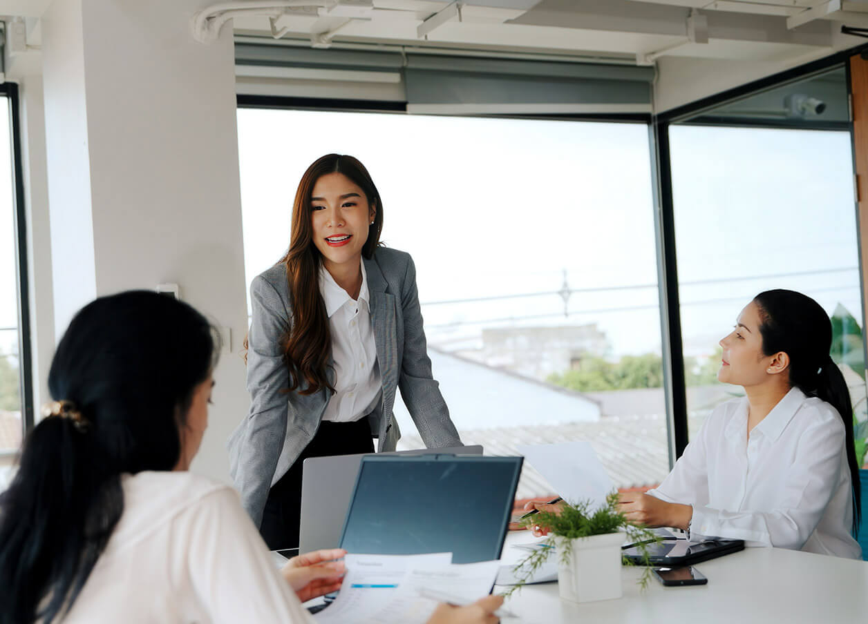A woman in a business suit engages in conversation with her colleagues in a professional setting.