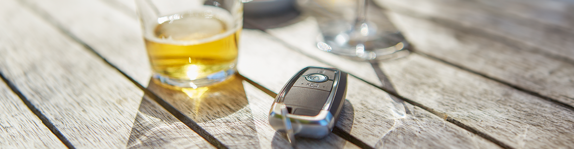 A half empty drink of spirits sitting on a table next to a car key