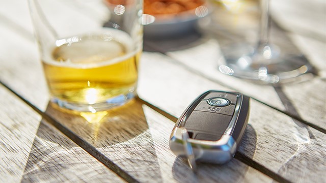 Nearly finished beer next to a car key on a table. 