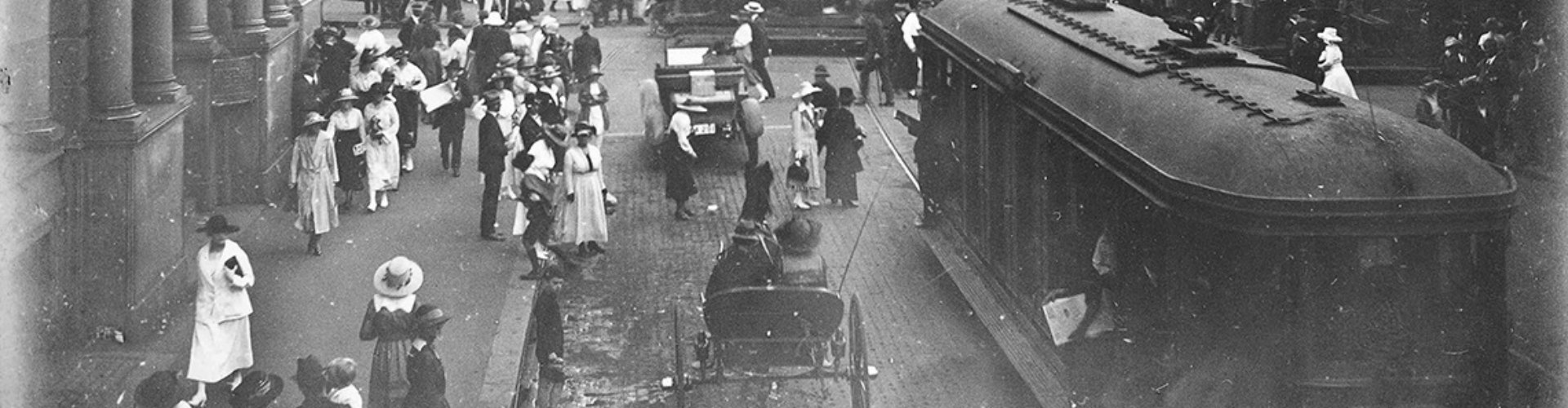 NRMA Centenary Founding Values header black and white photograph of busy Sydney CBD road with pedestrians, horse and cart, tram and early car