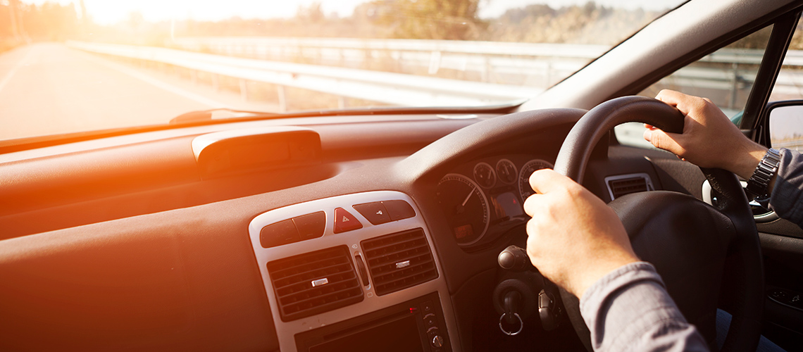 Steering wheel and dashboard of a car on the road