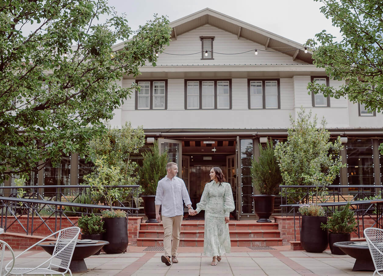 A couple joyfully holding hands in front of their Hotel accommodation, symbolising love and togetherness