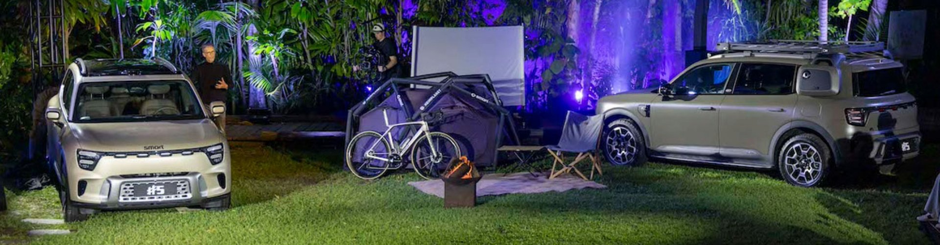 Two 2024 Smart #5 EVs parked on grassy, camp site terrain in a night setting.