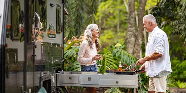 An older couple cooking next to their campervan
