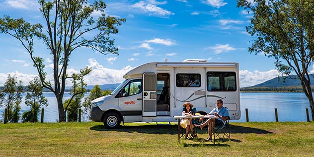 a couple sit outside a campervan