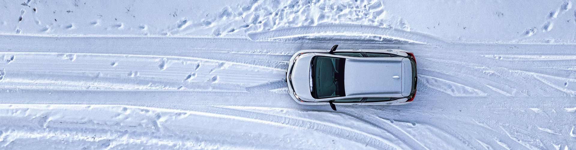 Drone shot of a car driving in snow