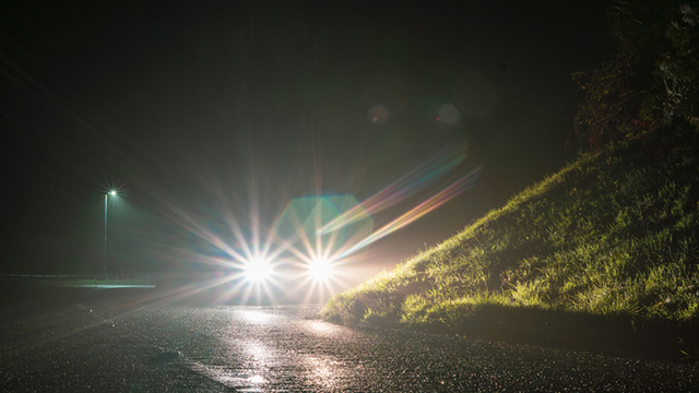 A car using its high beams on a dark road
