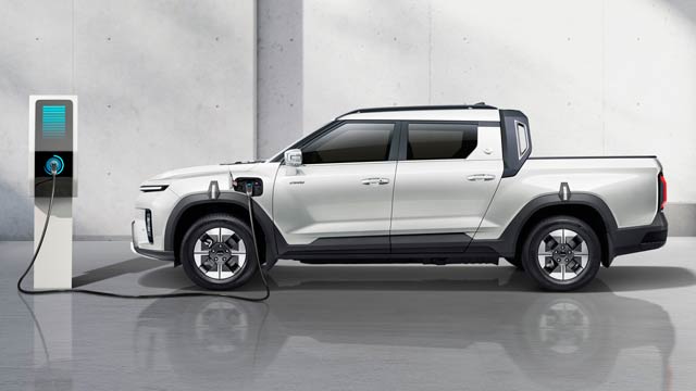 A white electric ute charging against a white wall