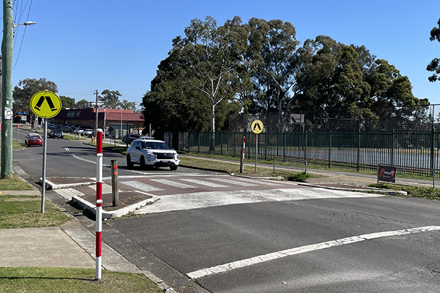 A white car driving near a pedestrian crossing