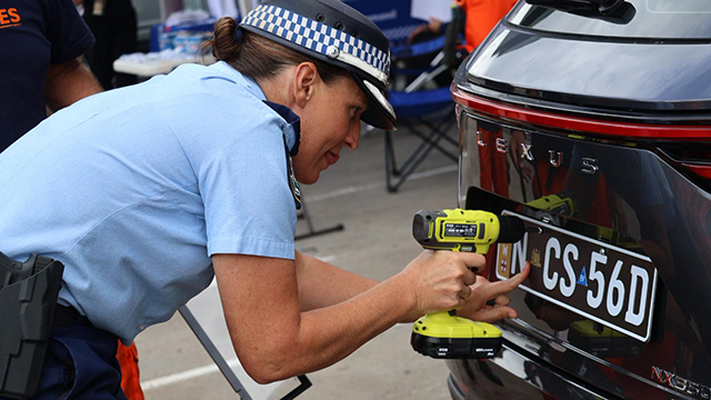 Police woman screwing in a car's number plate