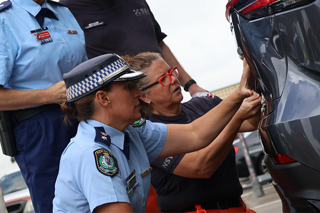 Police officer with car owner installing number plates on the rear of a car