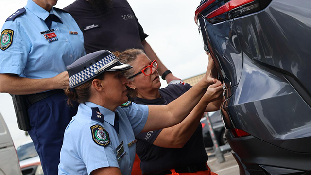 Police officer with car owner installing number plates on the rear of a car