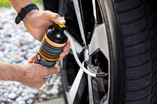 Man using a tyre repair kit to inflate a flat tyre