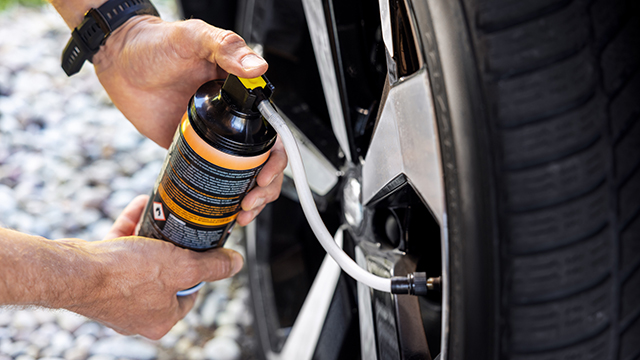 Man using a tyre repair kit to inflate a flat tyre