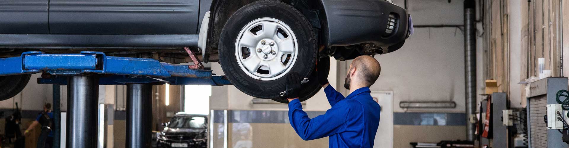 A mechanic repairing underside of a vehicle