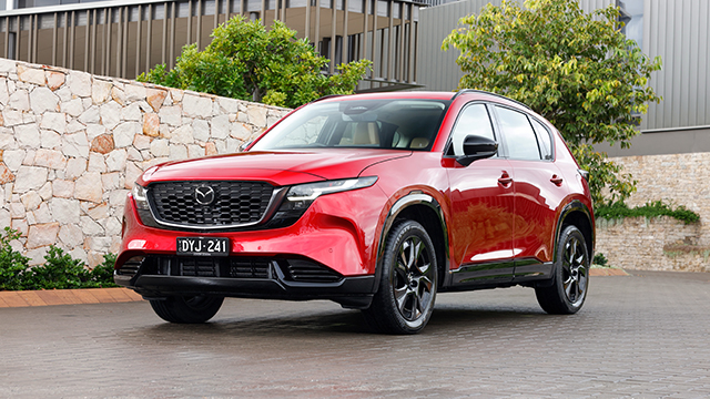 A red Mazda CX-5 parked near a stone wall