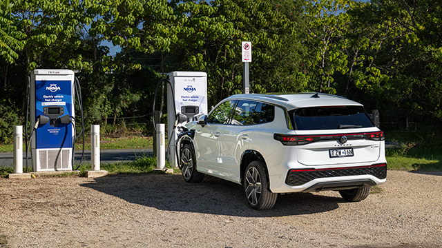 An electric vehicle charging up near trees