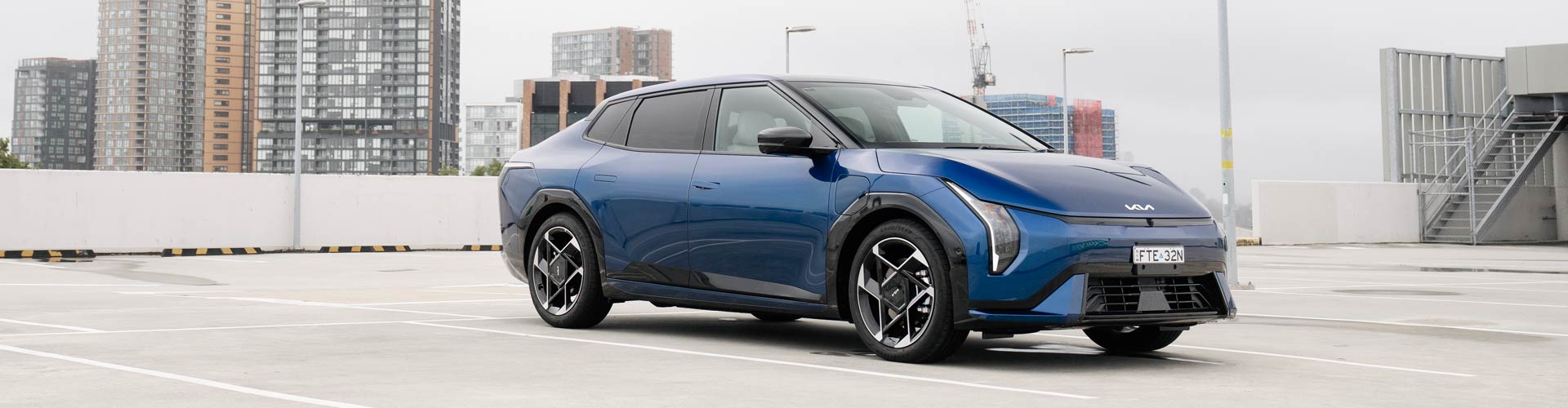 Side view pf a blue Kia EV4 electric car parked in a carpark