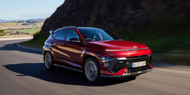 Red SUV driving around a corner of a hill