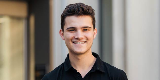 A young man with short dark hair wearing a black polo shirt