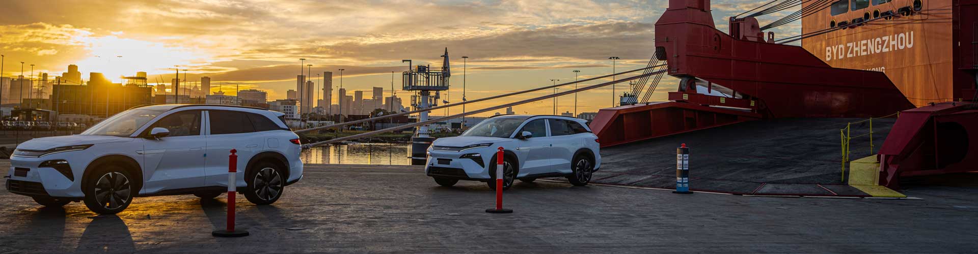 Two cars rolls off a cargo ship at sunset