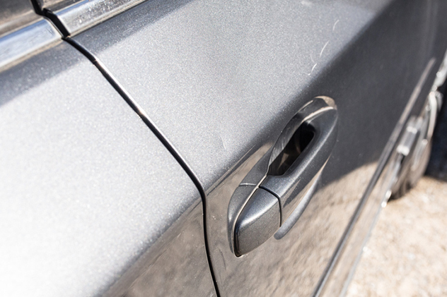 A grey car door with scratched paint