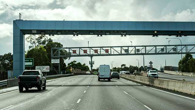 Driving towards electronic toll booth on highway Cars pass under an overhead boom on a Sydney toll road