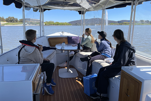 People in an electric boat on Lake Burley Griffin