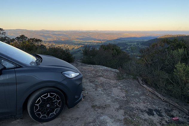 A grey car parked at a lookout at dawn
