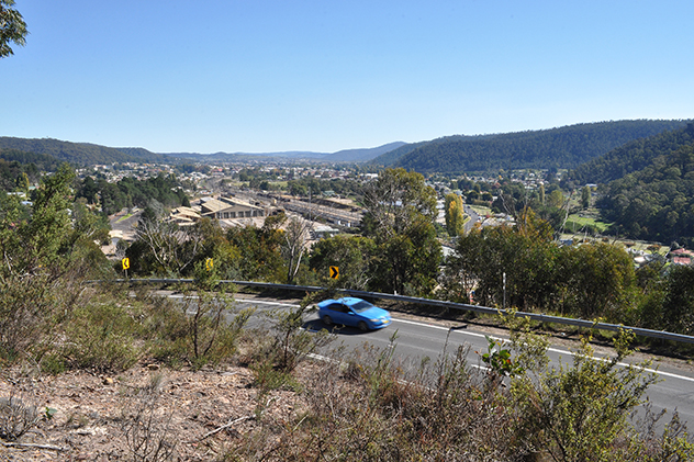 A blue car driving past a country town