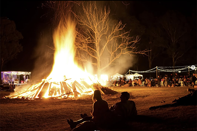 People sitting near a large bonfire
