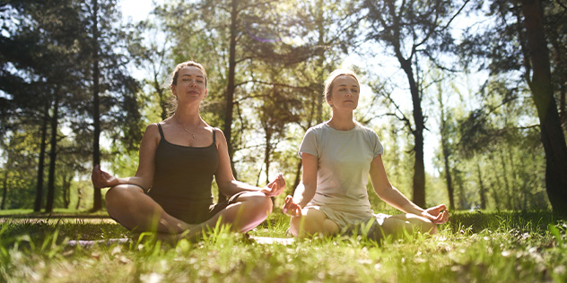 two women doing yoga outdoors