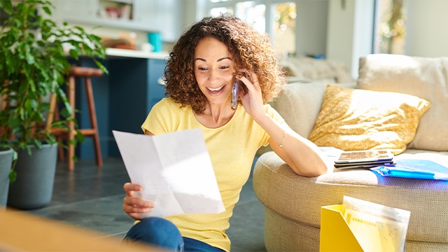 A woman reading a piece of paper and speaking on her phone