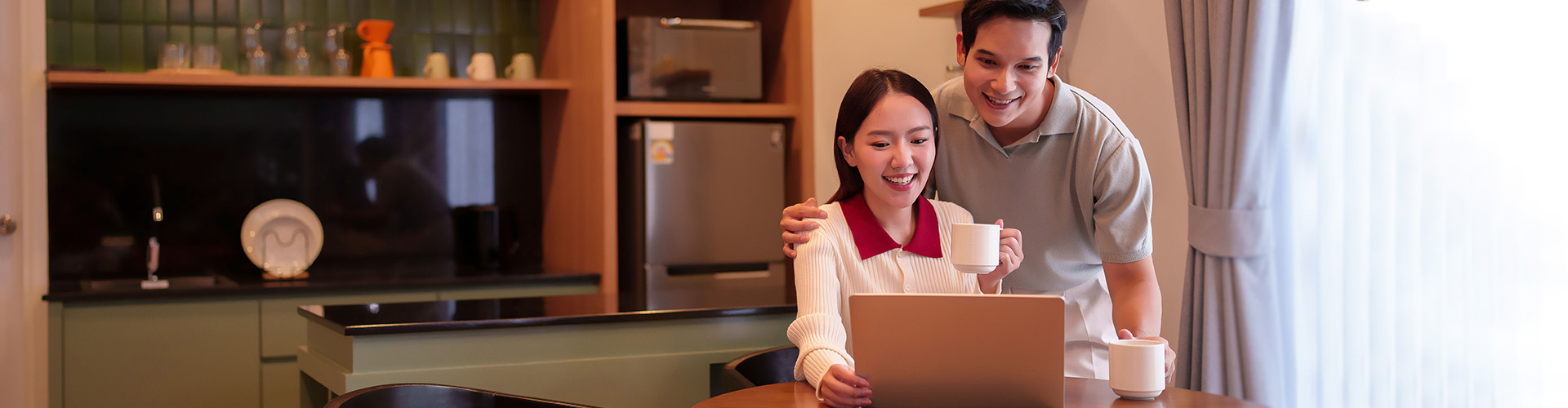 A couple look at a computer screen while drinking coffee